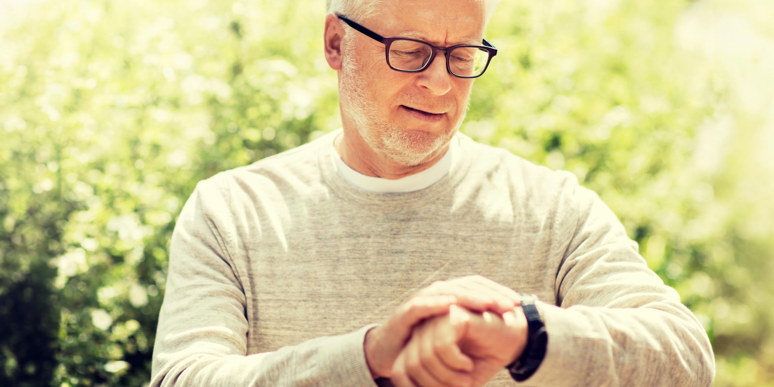Mann mittleren Alters prüft die Uhrzeit oder den Puls